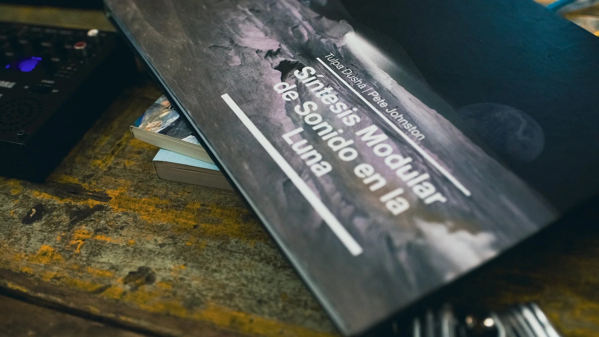Libro oficial de estudio de Modular Moon abierto sobre una mesa rodeado de cables