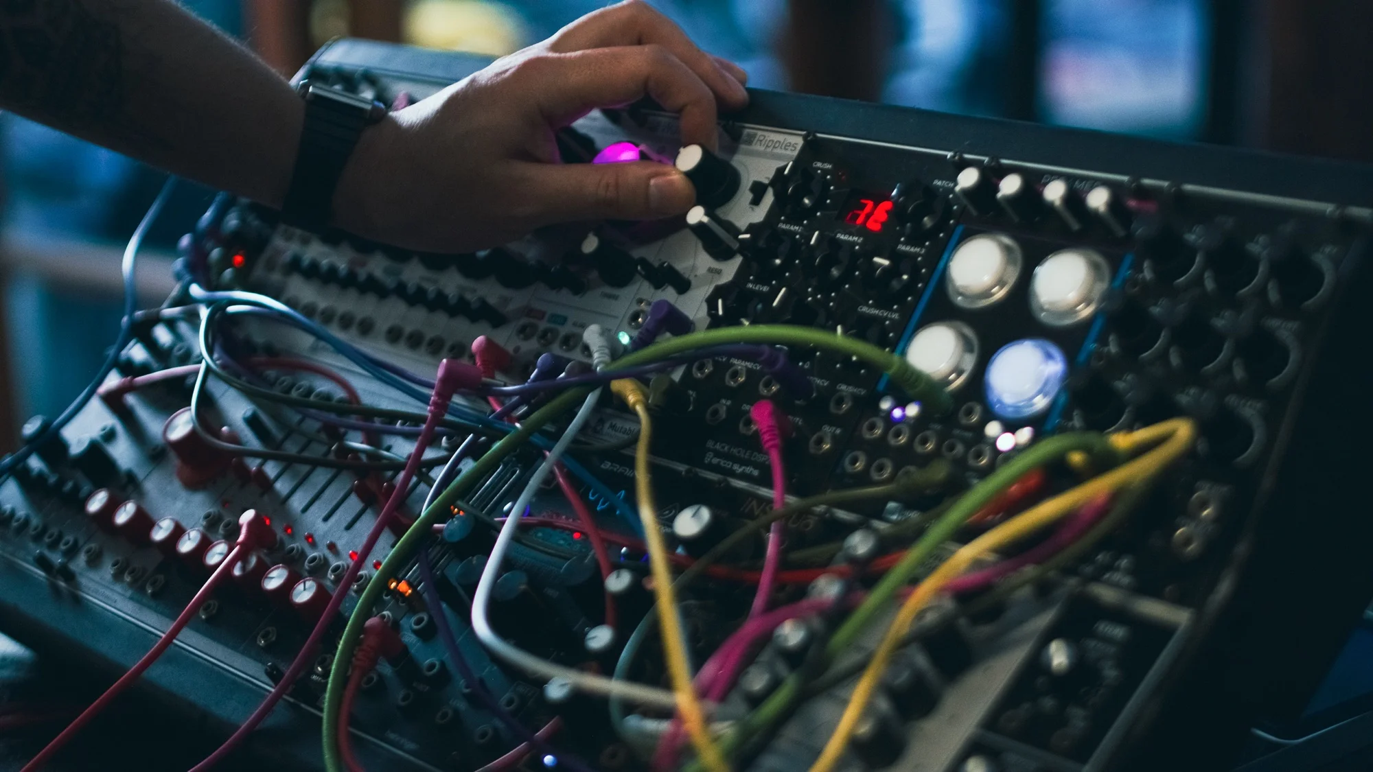 Mano de un estudiante ajustando perillas en un sistema de sintetizador modular TipTop Audio Buchla